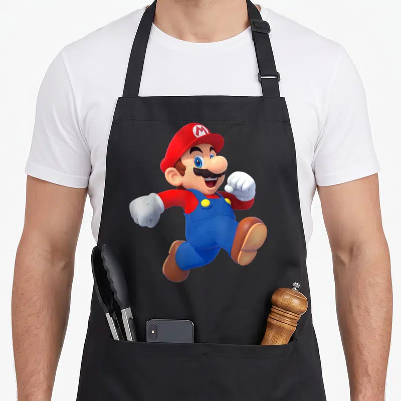 Poster running apron - Mario character jumping in red hat blue overalls white gloves brown shoes — shown on a black cotton canvas apron against a white background