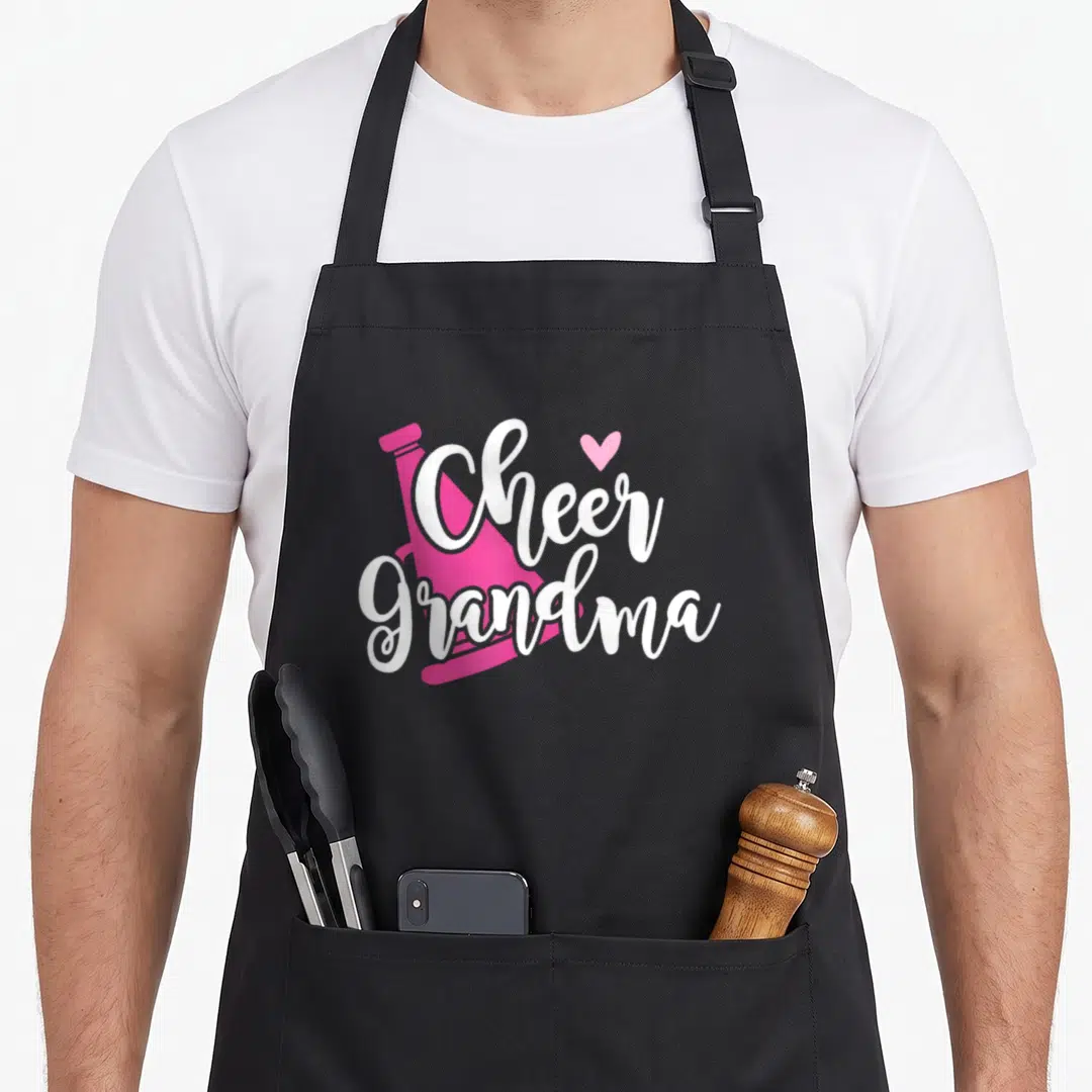 Cheer grandma apron - Pink megaphone with white Cheer Grandma script and small heart — shown on a black cotton canvas apron against a white background