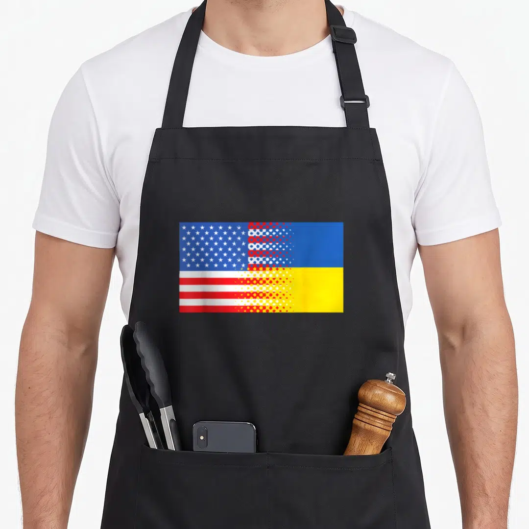Retro ukrainian american flag apron - Merged US and Ukraine flags blending via halftone dot pattern in blue red white — shown on a black cotton canvas apron against a white background
