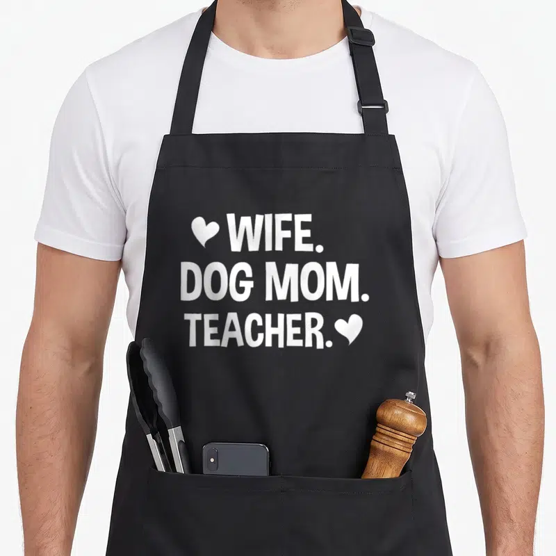 Dog best teacher apron - White WIFE DOG MOM TEACHER text with two hearts on grey background — shown on a black cotton canvas apron against a white background