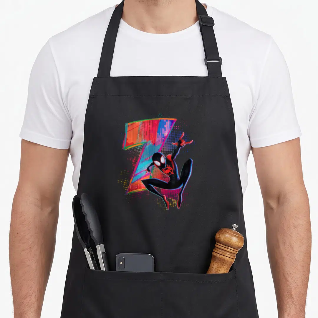 Morale 7th birthday apron - Miles Morales in black suit posing next to colorful glitch art number seven with halftone — shown on a black cotton canvas apron against a white background