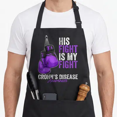 Glove ribbon apron - Purple boxing gloves with His Fight Is My Fight text and Crohn's Disease Awareness ribbon — shown on a black cotton canvas apron against a white background