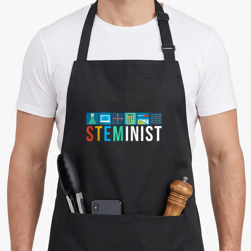 Steminist science apron - Six colored square icons with STEM tools above multi-colored STEMINIST text — shown on a black cotton canvas apron against a white background