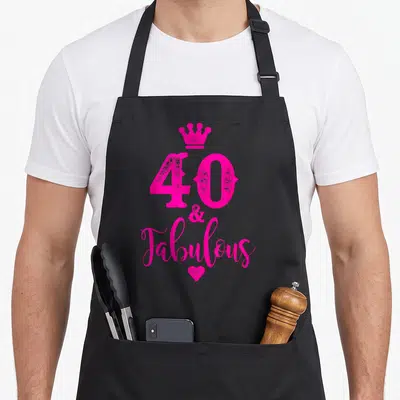 Forty fabulous 40th birthday apron - Pink 40 ampersand Fabulous text with crown and heart stacked vertically — shown on a black cotton canvas apron against a white background