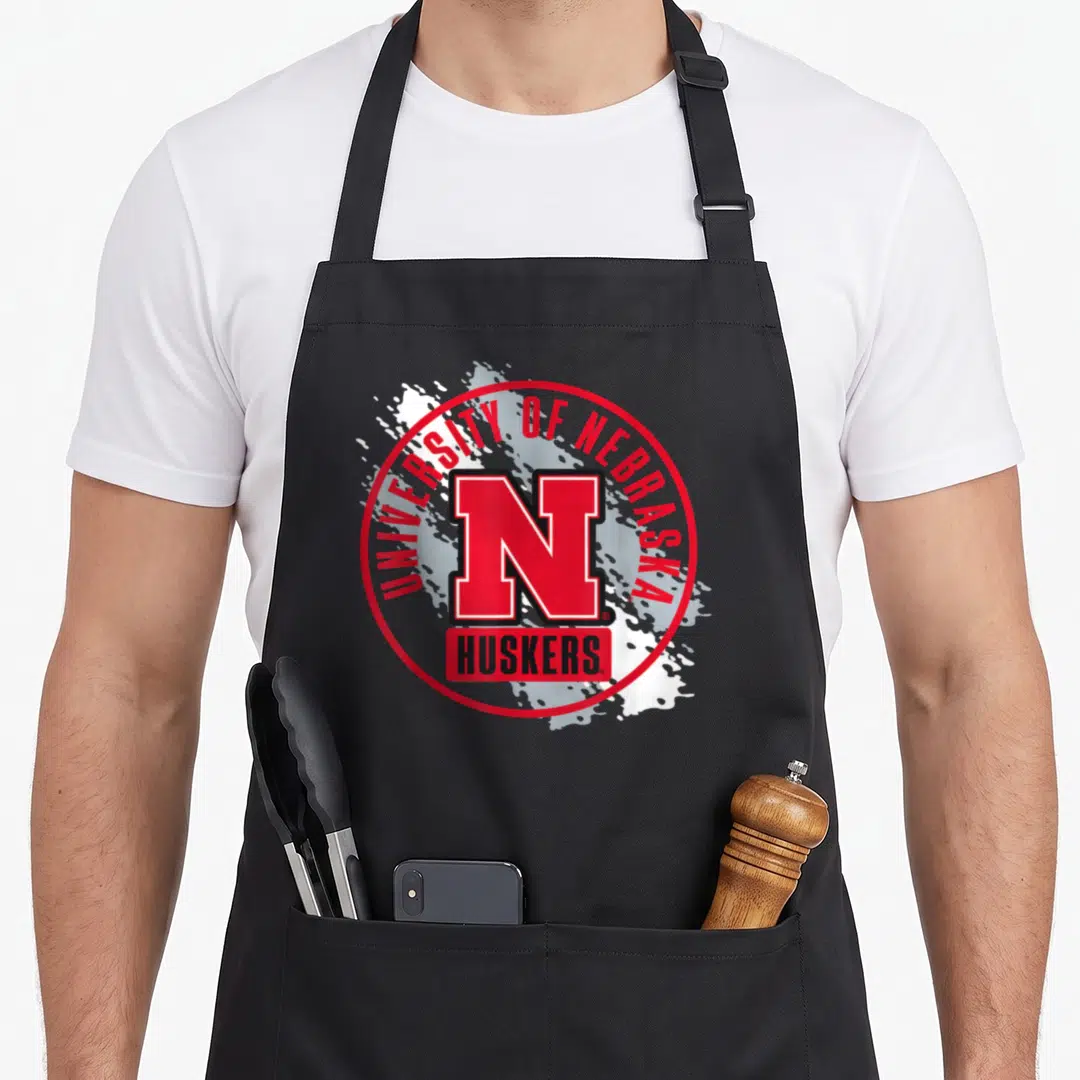 Nebraska paint apron - Red N logo University of Nebraska Huskers white splatter — shown on a black cotton canvas apron against a white background
