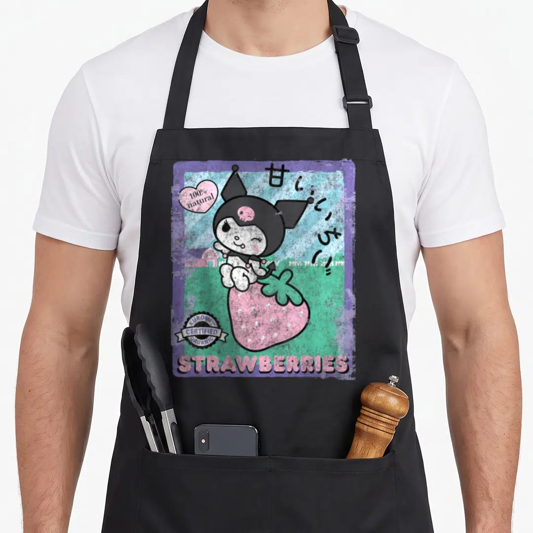 Strawberry farm apron - Kuromi sitting on pink strawberry with 100% natural text and Japanese characters — shown on a black cotton canvas apron against a white background