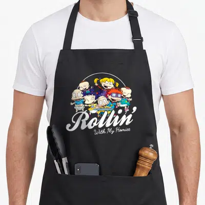 Rollin baby apron - Cartoon babies clustered above white script text reading Rollin With My Homies on black fabric — shown on a black cotton canvas apron against a white background