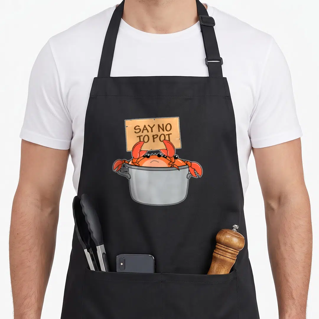 Boil crab apron - Cartoon crab in grey pot holding tan sign saying SAY NO TO POT — shown on a black cotton canvas apron against a white background