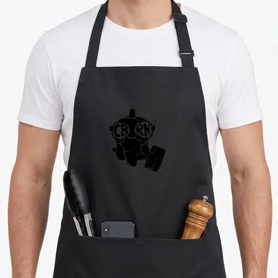 Gas military apron - Distressed black gas mask silhouette with CBRN text in white eye lenses — shown on a black cotton canvas apron against a white background