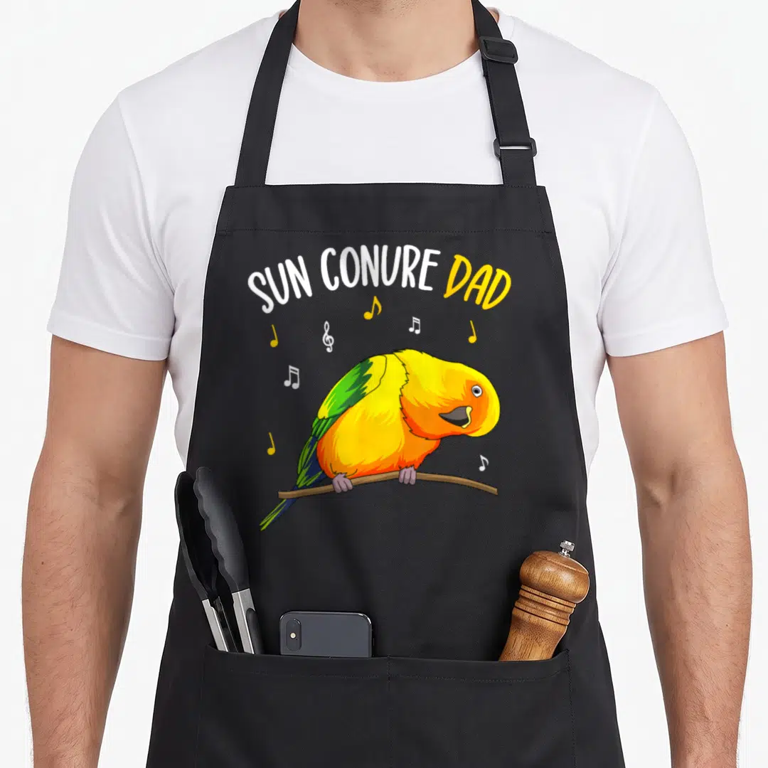 Sun conure bird apron - Cartoon sun conure perched on branch with musical notes and arched text SUN CONURE DAD — shown on a black cotton canvas apron against a white background