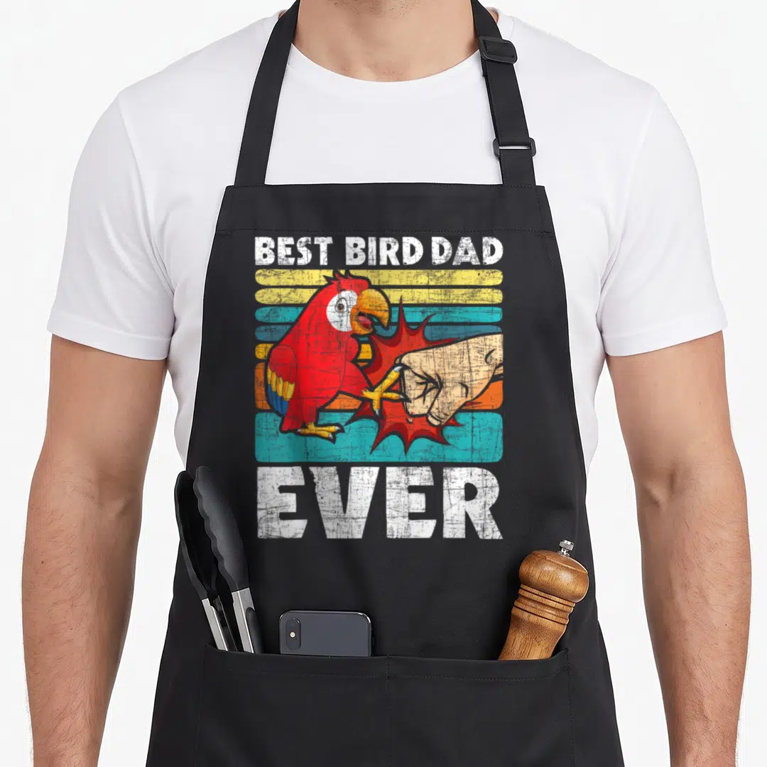 Zookeeper birdwatcher bird apron - Cartoon red parrot clamping a hand with red explosion on yellow blue tan stripes — shown on a black cotton canvas apron against a white background