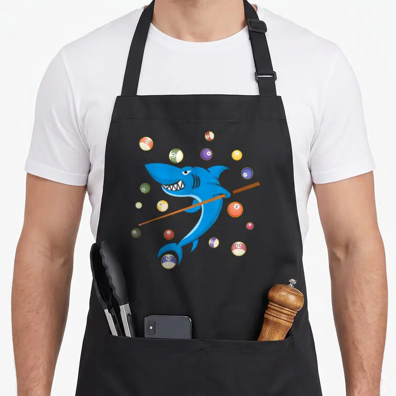 Shark pool table apron - Cartoon blue shark holding brown pool cue surrounded by colorful billiard balls — shown on a black cotton canvas apron against a white background
