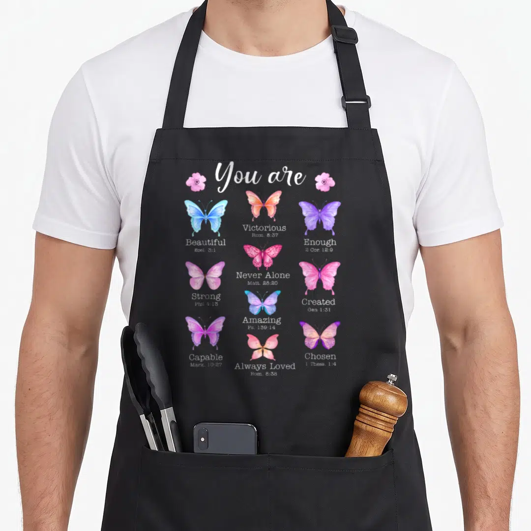 Beautiful bible verse apron - Watercolor butterflies with scripture verses like Victorious and Chosen on black bib — shown on a black cotton canvas apron against a white background