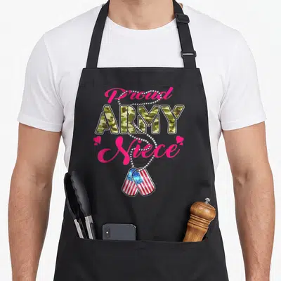 Niece tag apron - Proud ARMY Niece text with camo letters, silver chain, two US flag dog tags, and pink hearts — shown on a black cotton canvas apron against a white background