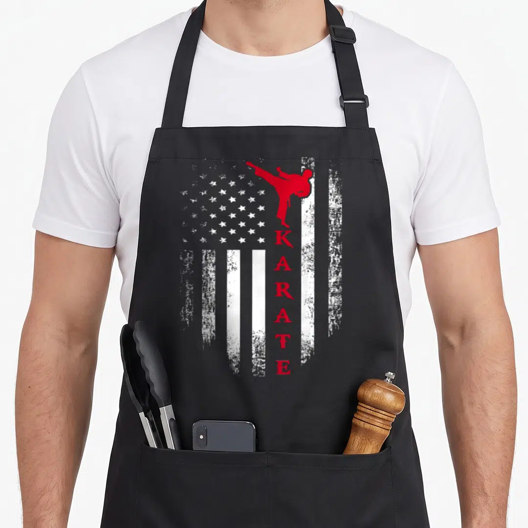 Karate american flag apron - Red karateka silhouette over distressed white stripes with vertical KARATE text — shown on a black cotton canvas apron against a white background