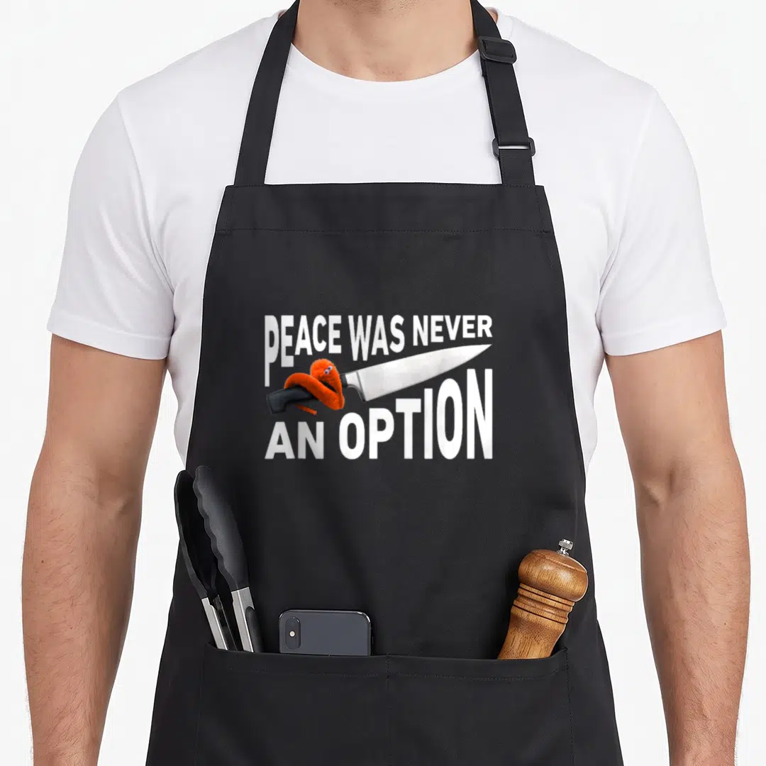 Option meme apron - Silver knife with orange monster and text PEACE WAS NEVER AN OPTION — shown on a black cotton canvas apron against a white background