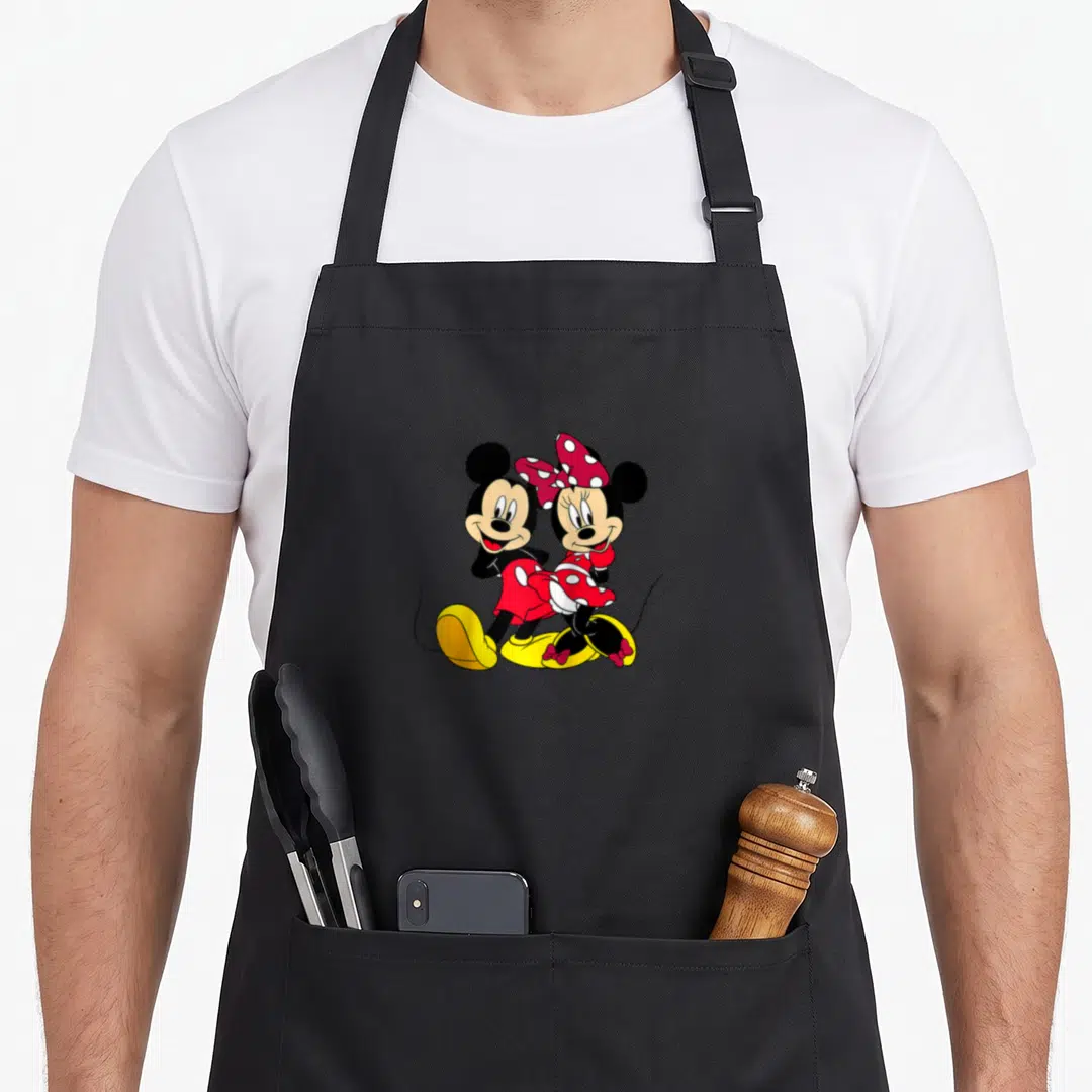Mouse baseball apron - Mickey and Minnie Mouse cartoon standing side-by-side in red and yellow — shown on a black cotton canvas apron against a white background