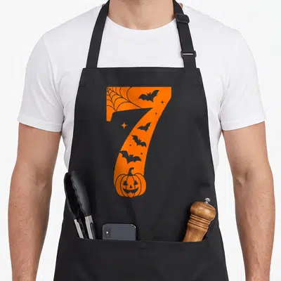 Meme couple halloween apron - Large orange number 7 containing grey bats, spider web, stars, and pumpkin silhouette — shown on a black cotton canvas apron against a white background