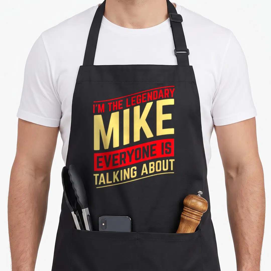 Mike christmas aprons - Red and yellow stacked text reading I'M THE LEGENDARY MIKE EVERYONE IS TALKING ABOUT — shown on a black cotton canvas apron against a white background
