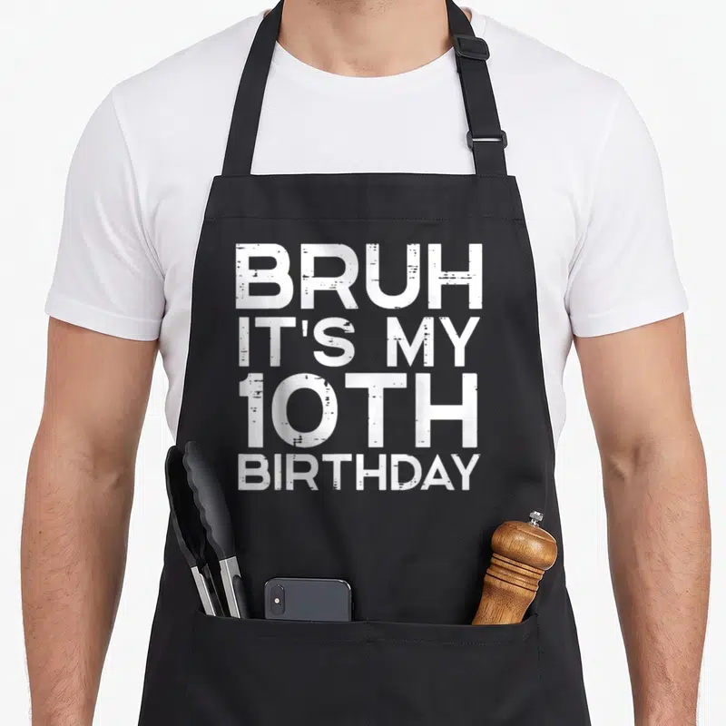 Bruh 10th bday birthday apron - White distressed text reading BRUH IT'S MY 10TH BIRTHDAY stacked vertically — shown on a black cotton canvas apron against a white background