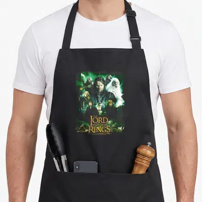 Hero ring apron - Aragorn and fellowship photo montage with stacked Lord of the Rings text in green grey gold — shown on a black cotton canvas apron against a white background