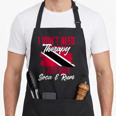 Soca my therapy apron - I Don't Need Therapy I Just Need Soca & Rum text with red white black flag paint stroke — shown on a black cotton canvas apron against a white background