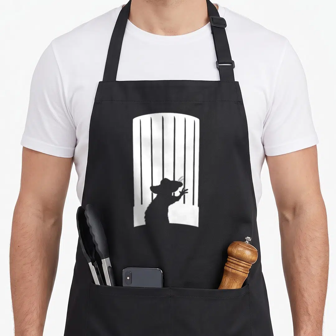 Silhouette remy ratatouille apron - Grey mouse silhouette reaching white vertical chef hat bars minimalist design — shown on a black cotton canvas apron against a white background