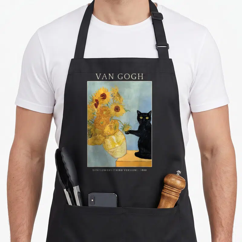 Cat van gogh apron - Black cat reaching for yellow sunflowers in a vase under Van Gogh text label — shown on a black cotton canvas apron against a white background