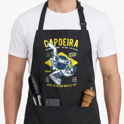 Brazilian capoeira apron - Two capoeira practitioners over yellow blue flag with distressed Capoeira text — shown on a black cotton canvas apron against a white background