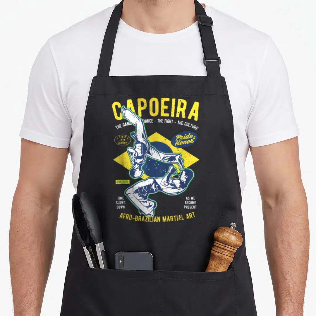 Brazilian capoeira apron - Two capoeira practitioners over yellow blue flag with distressed Capoeira text — shown on a black cotton canvas apron against a white background