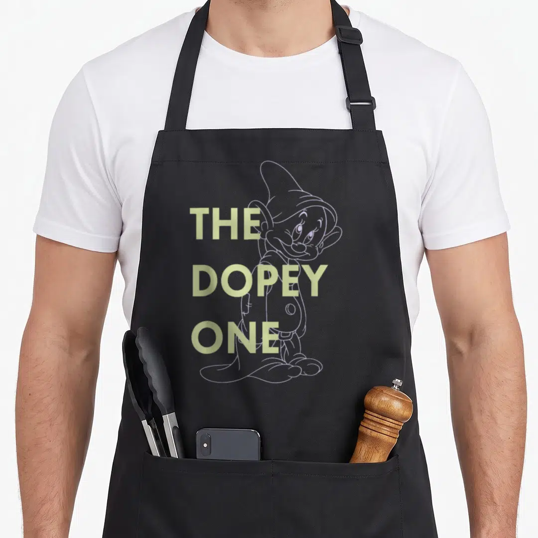 Dopey outlined snow white apron - The Dopey One text over purple dwarf outline — shown on a black cotton canvas apron against a white background
