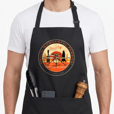 Wonderful mars apron - Retro circular drone design with Hello Wonderful Person text and red sun — shown on a black cotton canvas apron against a white background