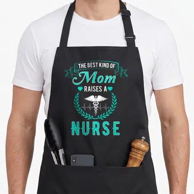 Raise white nurse apron - Teal and white text reading The Best Kind Of Mom Raises A Nurse with caduceus and hearts — shown on a black cotton canvas apron against a white background