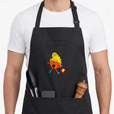 Fabulous mr apron - Little Miss Fabulous cartoon character holding a red handbag with yellow starburst — shown on a black cotton canvas apron against a white background