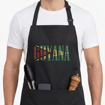 Flag guyanese apron - GUYANA text filled with green yellow red white and black flag stripes — shown on a black cotton canvas apron against a white background
