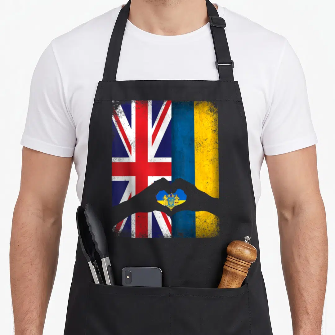 Ukrainian uk aprons - Two flags side-by-side with grey hands forming a heart containing a coat of arms in distressed — shown on a black cotton canvas apron against a white background