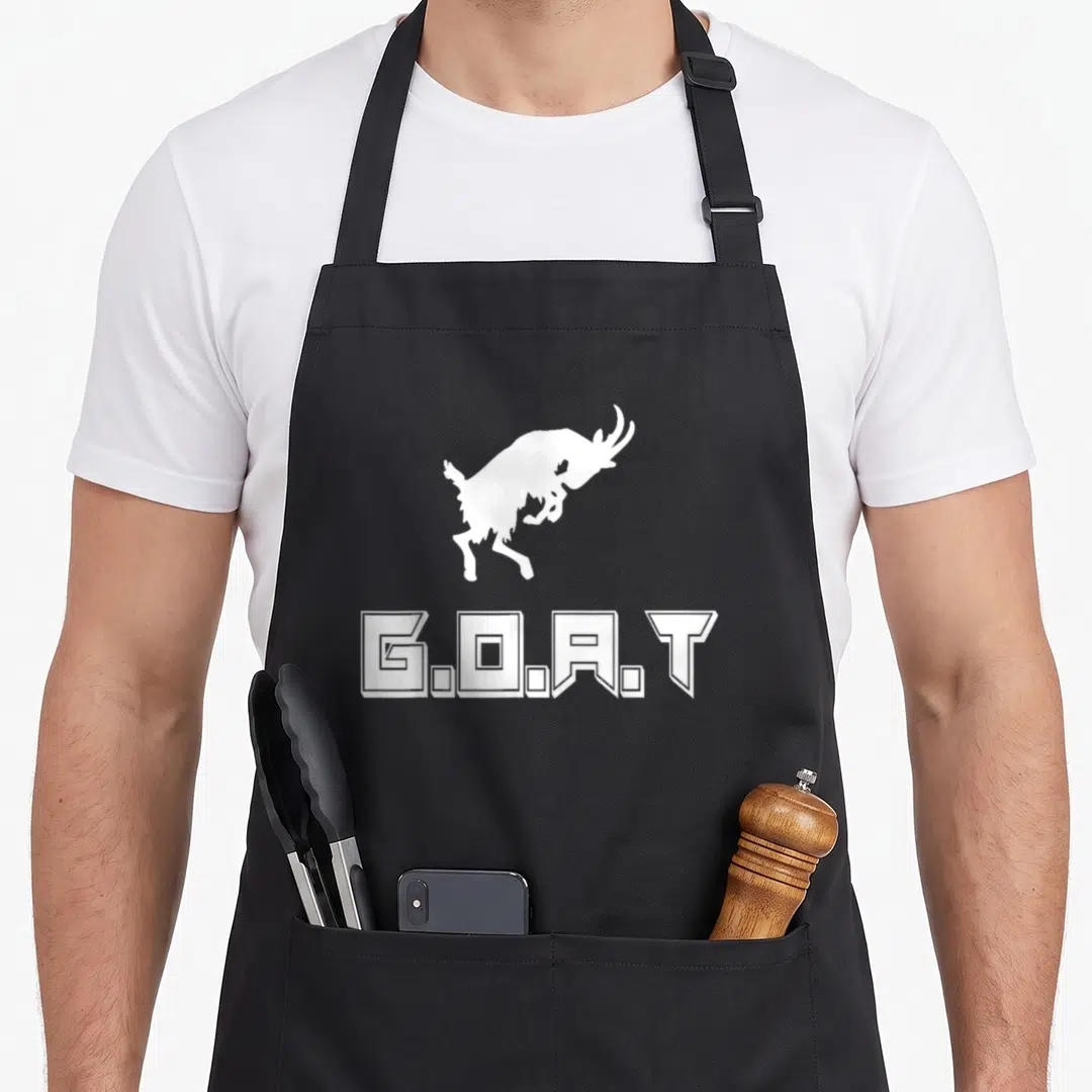 Funny greatest apron - White jumping goat silhouette above G.O.A.T block text — shown on a black cotton canvas apron against a white background