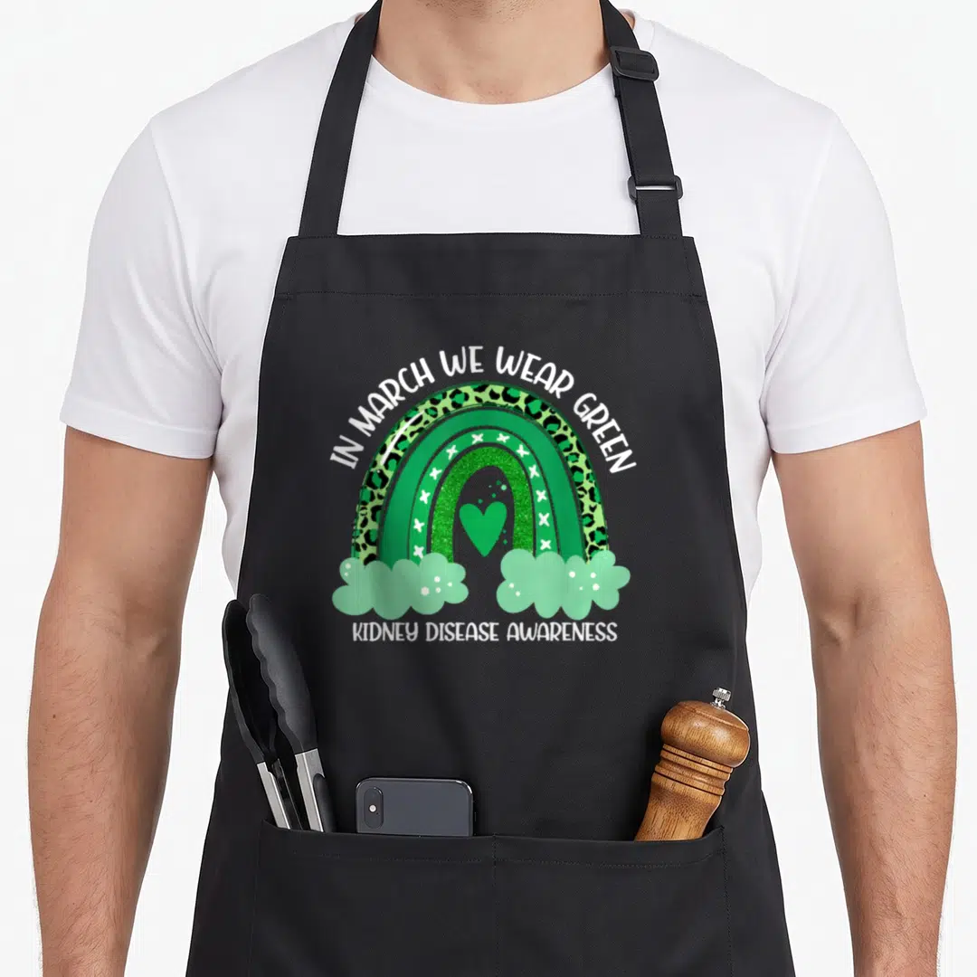 Kidney rainbow apron - Green rainbow with leopard print and heart displaying kidney disease awareness text — shown on a black cotton canvas apron against a white background