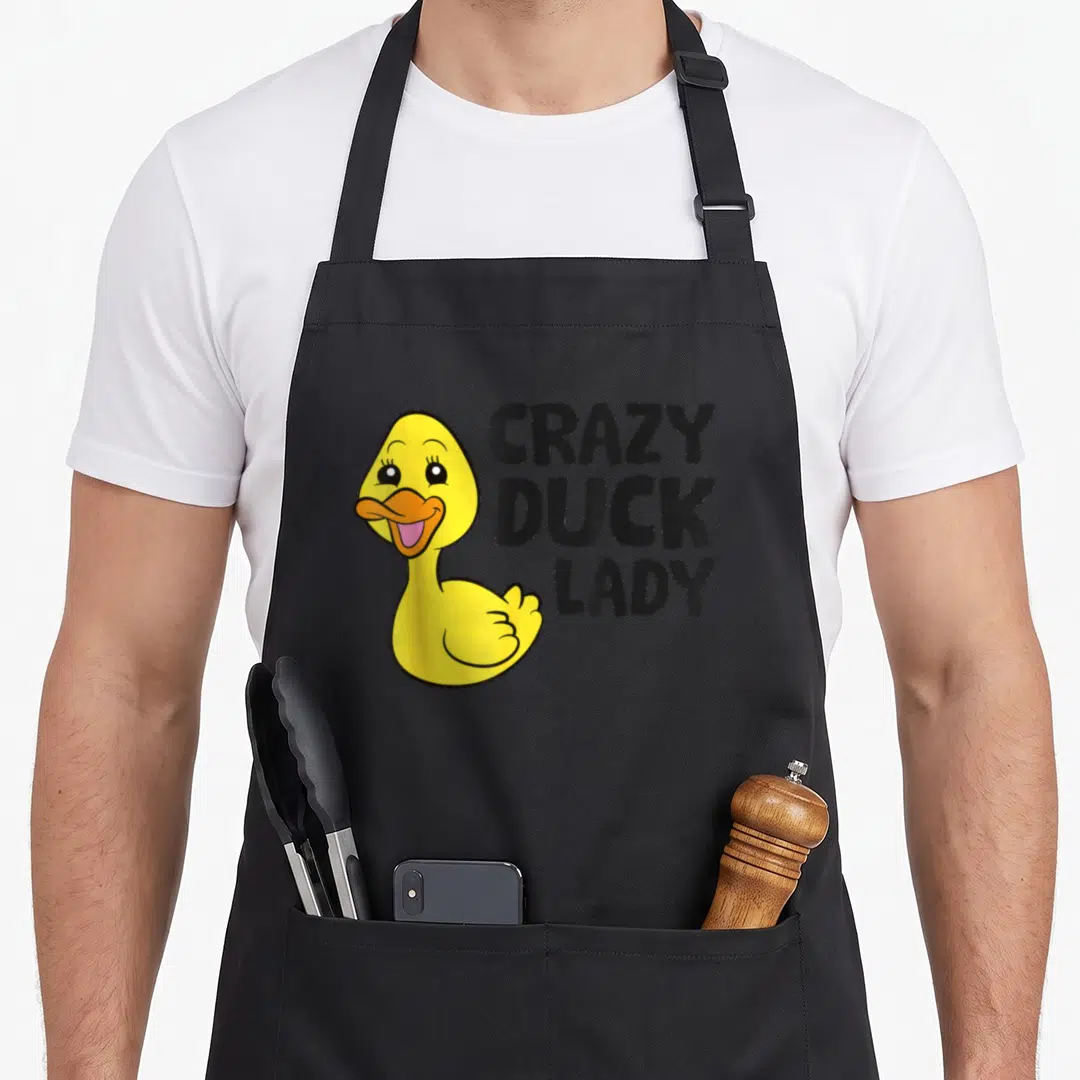 Funny cotton duck aprons - Yellow cartoon duck giving a thumbs up next to stacked black text reading CRAZY DUCK LADY — shown on a black cotton canvas apron against a white background