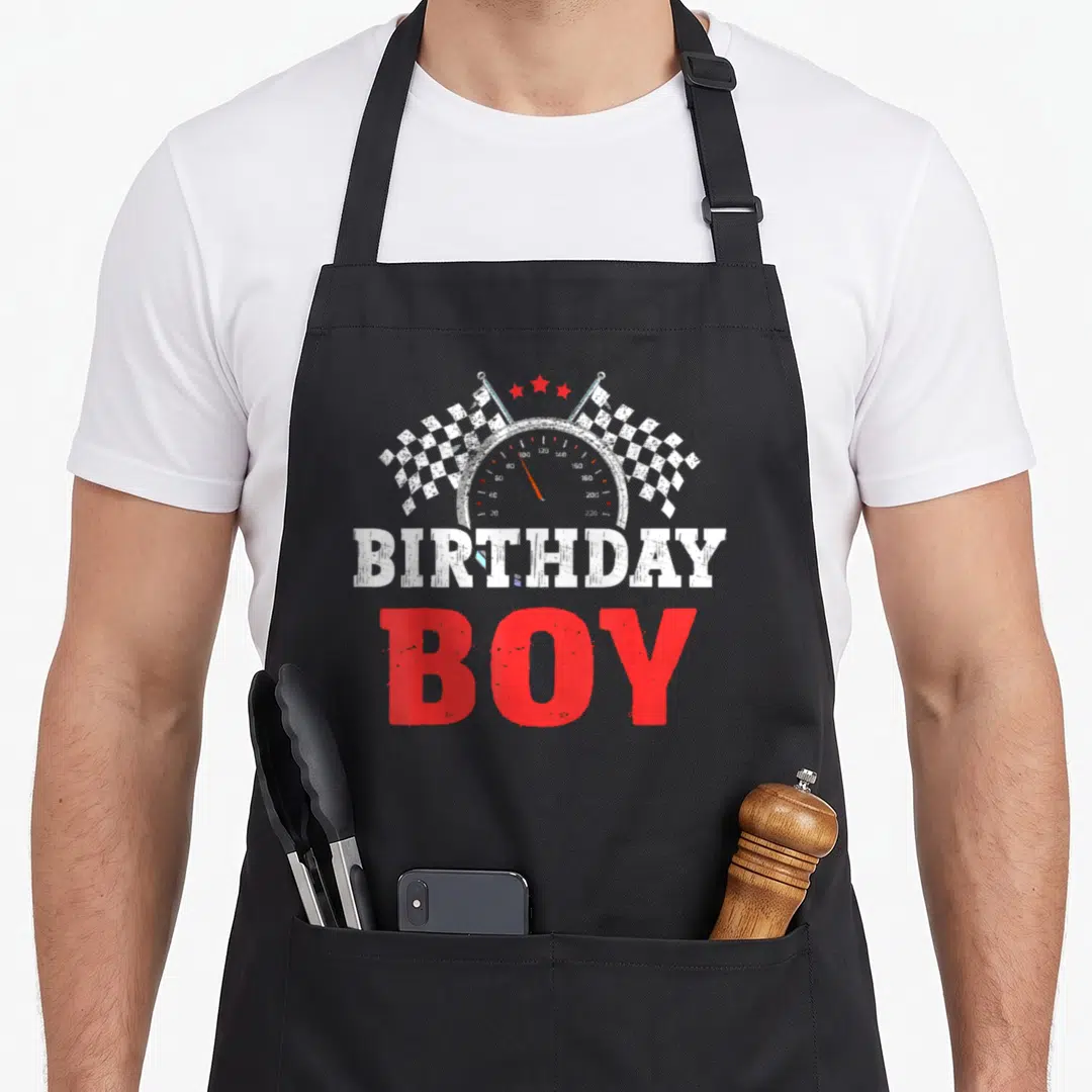 Driver car apron - Speedometer with checkered flags and BIRTHDAY BOY text in red white grey — shown on a black cotton canvas apron against a white background