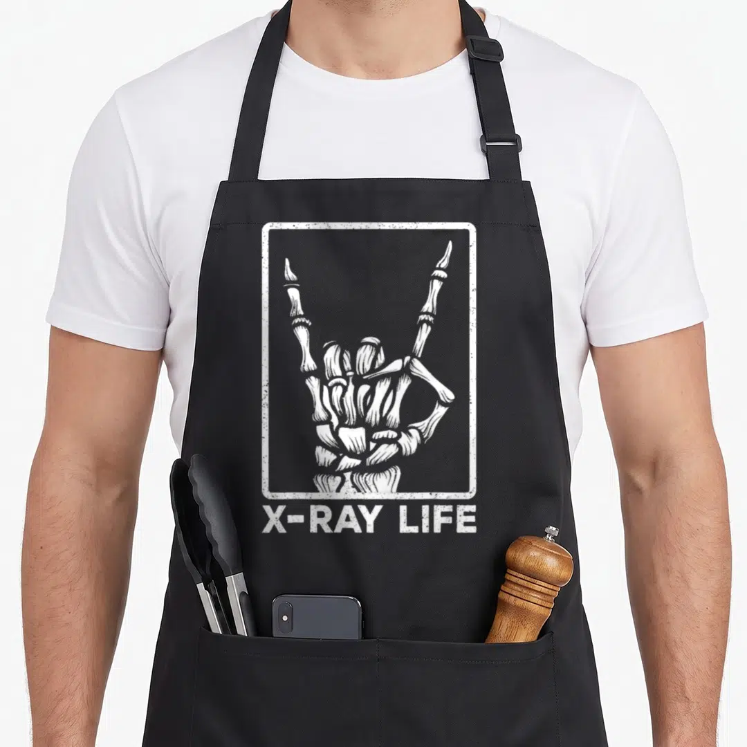 Xray halloween themed aprons - White skeleton hand in distressed frame with X-RAY LIFE text below — shown on a black cotton canvas apron against a white background