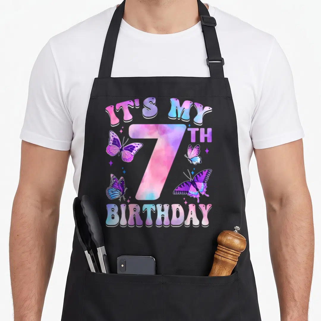 7th butterfly aprons - Number 7 IT'S MY BIRTHDAY text with pink purple blue butterflies and stars — shown on a black cotton canvas apron against a white background
