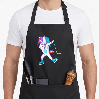 Hockey unicorn apron - Cartoon unicorn in ice skates holding a hockey stick with rainbow mane — shown on a black cotton canvas apron against a white background