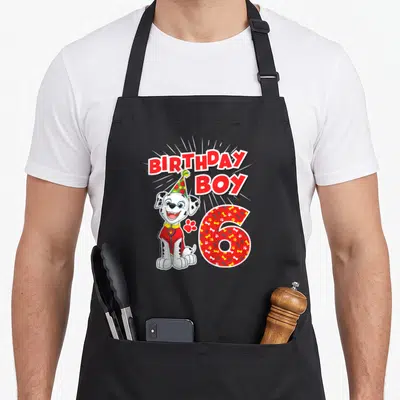 Merchandise marshalls apron - Dalmatian puppy wearing party hat next to red paw print and patterned number 6 — shown on a black cotton canvas apron against a white background