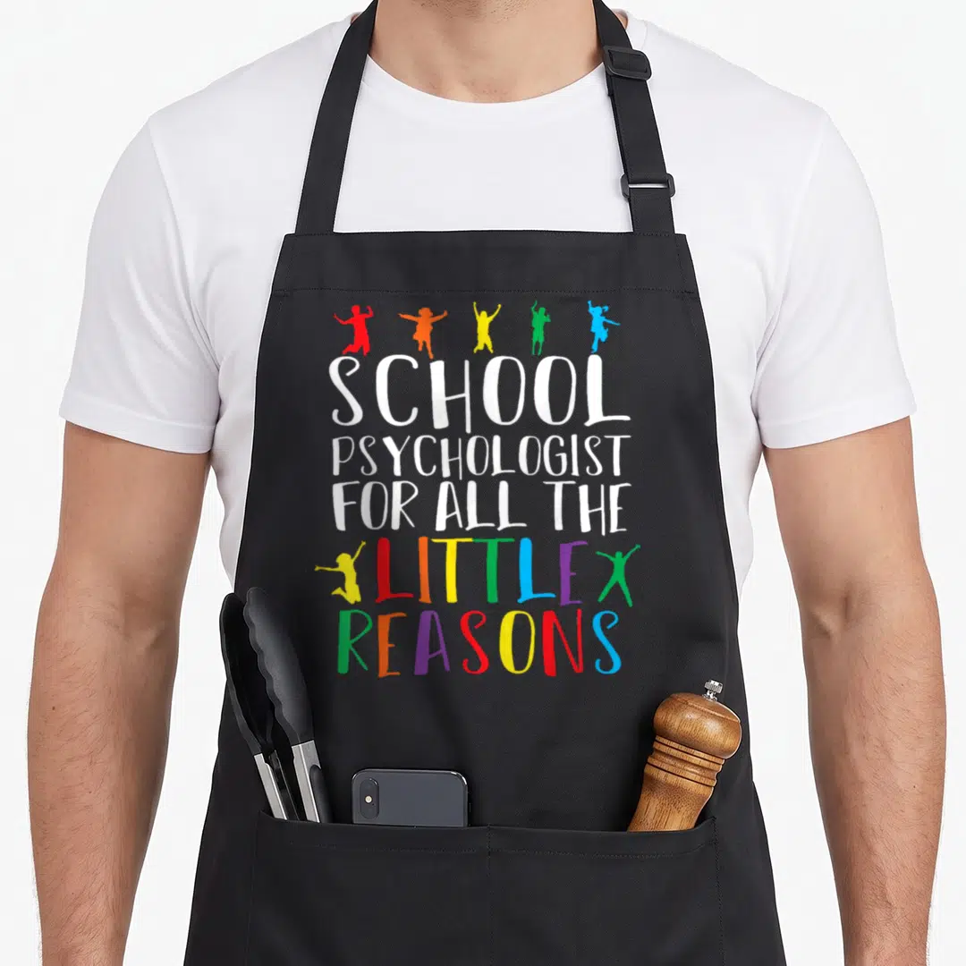 Reason psychologist apron - SCHOOL PSYCHOLOGIST text with five jumping child silhouettes in red orange yellow green — shown on a black cotton canvas apron against a white background