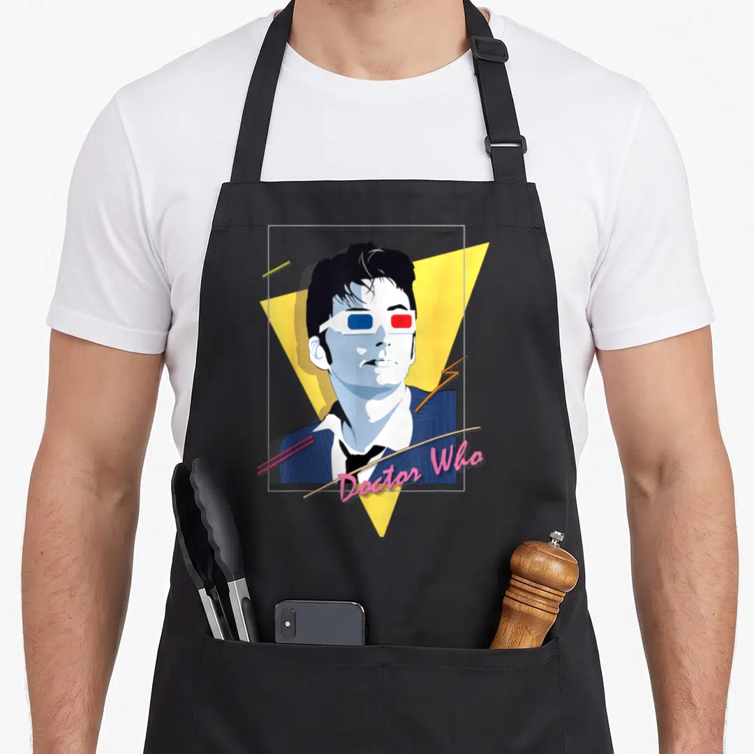 Tenant 80s apron - Retro man in 3D glasses over yellow triangle with pink Doctor Who script text — shown on a black cotton canvas apron against a white background