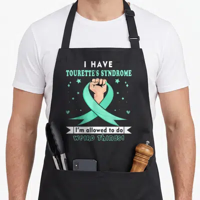 Retro syndrome tourette awareness apron - Fist holding mint green ribbon with text I have Tourette's Syndrome I'm — shown on a black cotton canvas apron against a white background