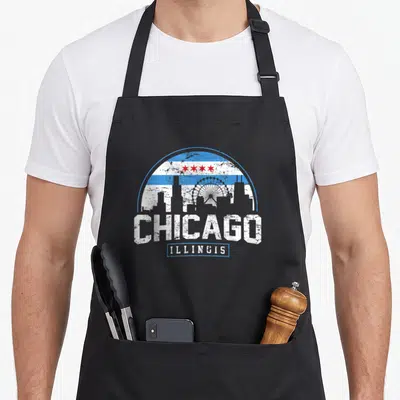 Illinois flag skyline chicago apron - Distressed white skyline silhouette under blue white stripes and four red stars — shown on a black cotton canvas apron against a white background