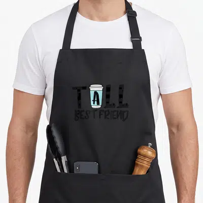 Tall coffee apron - TALL BEST FRIEND text with blue coffee cup replacing the letter A in cartoon style — shown on a black cotton canvas apron against a white background