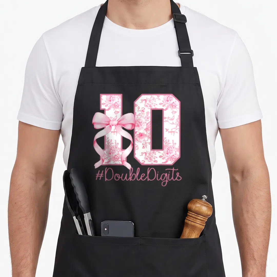 10th bow apron - Number 10 filled with pink roses and a ribbon bow with hashtag text — shown on a black cotton canvas apron against a white background